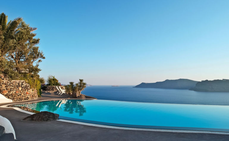 Infinity swimming pool overlooking the ocean with palm trees